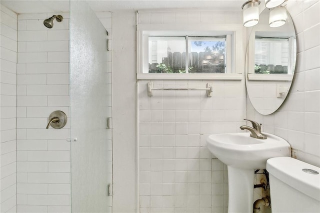 bathroom with a stall shower, toilet, and tile walls