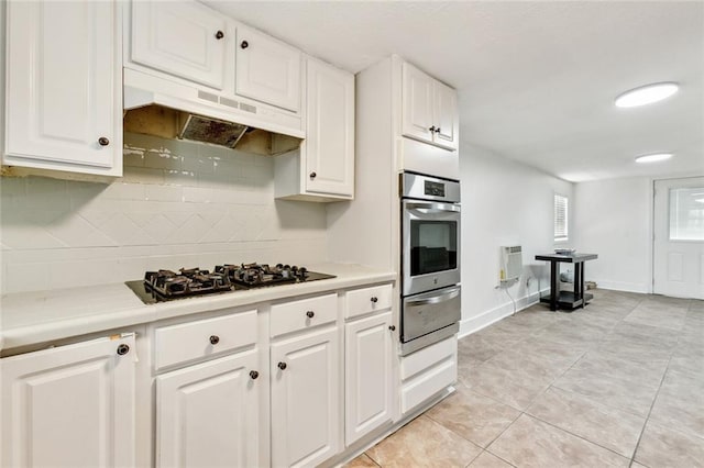 kitchen featuring oven, under cabinet range hood, light countertops, black gas stovetop, and a warming drawer