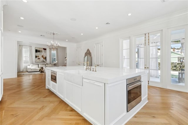 kitchen with sink, white cabinetry, an island with sink, pendant lighting, and stainless steel appliances