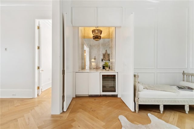 bar with white cabinets, light parquet flooring, and wine cooler