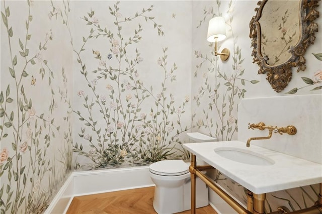 bathroom featuring parquet flooring, toilet, and sink