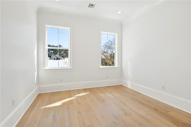 unfurnished room with crown molding, a wealth of natural light, and light hardwood / wood-style floors