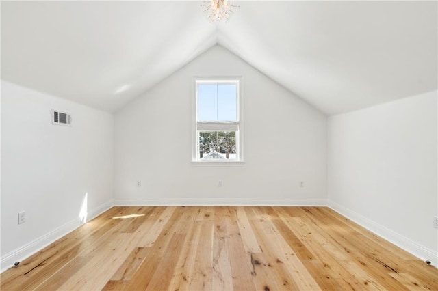 additional living space with wood-type flooring and vaulted ceiling