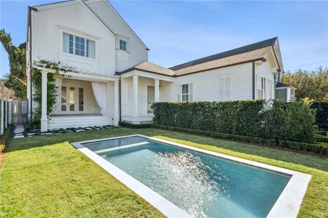 rear view of property with a fenced in pool and a lawn