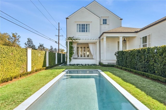 rear view of house featuring a fenced in pool and a yard