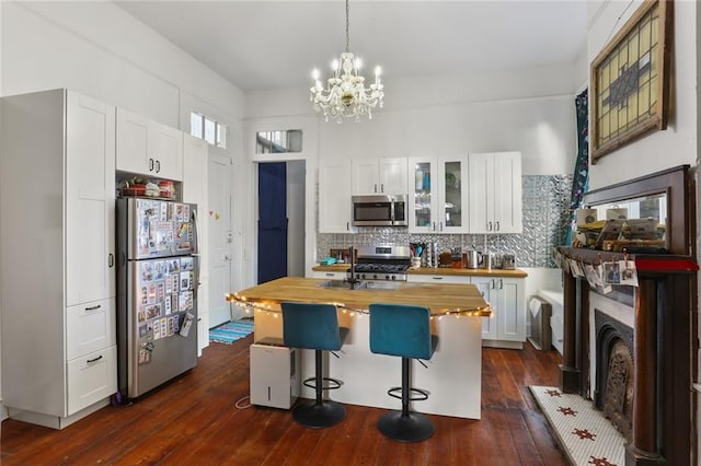 kitchen with a kitchen island, white cabinets, wooden counters, a kitchen bar, and stainless steel appliances