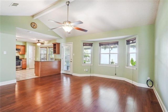 unfurnished living room with ceiling fan, a wealth of natural light, light hardwood / wood-style flooring, and vaulted ceiling with beams