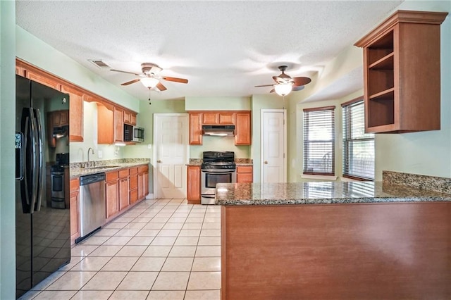 kitchen with stainless steel appliances, a textured ceiling, and stone countertops