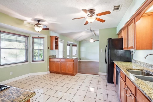 kitchen with sink, a textured ceiling, light tile patterned flooring, vaulted ceiling, and stainless steel dishwasher