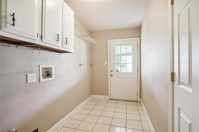 washroom with cabinets, light tile patterned flooring, hookup for a washing machine, and a textured ceiling