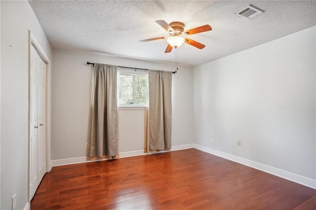 unfurnished room featuring ceiling fan, dark hardwood / wood-style flooring, and a textured ceiling