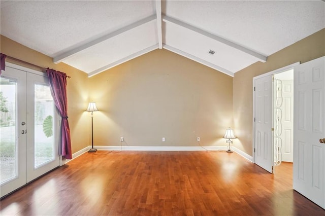 empty room featuring hardwood / wood-style flooring, plenty of natural light, vaulted ceiling with beams, and french doors