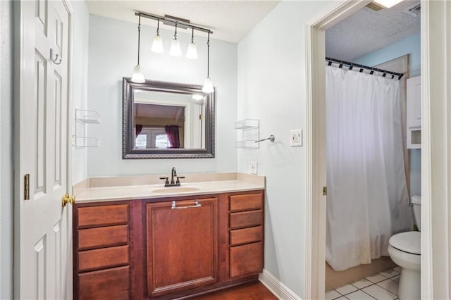 bathroom featuring tile patterned floors, vanity, toilet, and a textured ceiling