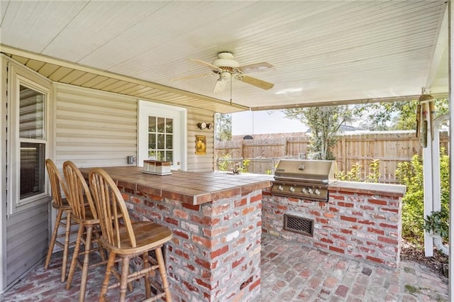 view of patio / terrace with exterior kitchen, a grill, ceiling fan, and a bar