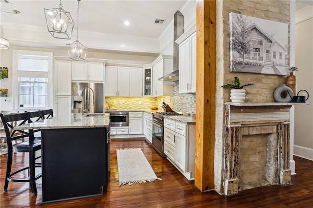 kitchen with light stone countertops, stainless steel appliances, white cabinets, and a center island with sink