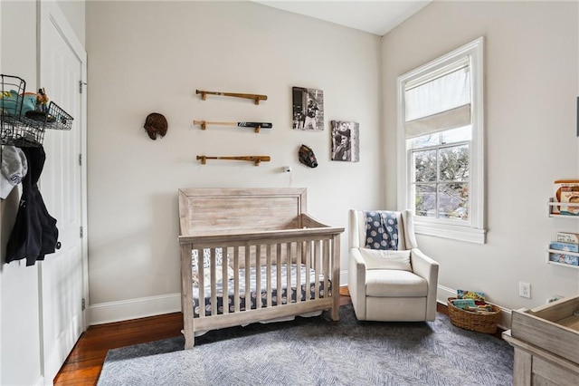 bedroom featuring dark wood-type flooring and a crib