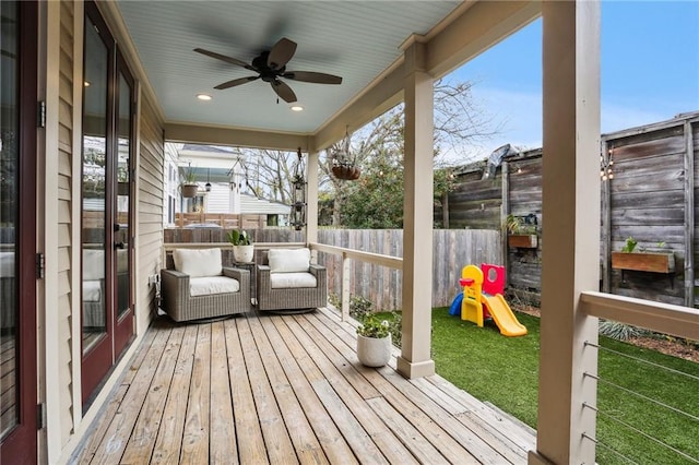 wooden terrace with a playground, a yard, an outdoor living space, and ceiling fan