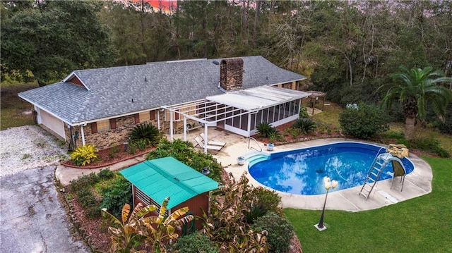 view of pool featuring a sunroom, a patio area, and a lawn