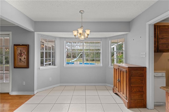 dining space featuring light tile patterned floors, a textured ceiling, baseboards, and a notable chandelier