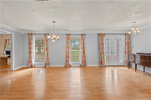 unfurnished dining area with light wood-type flooring, a wealth of natural light, and a notable chandelier