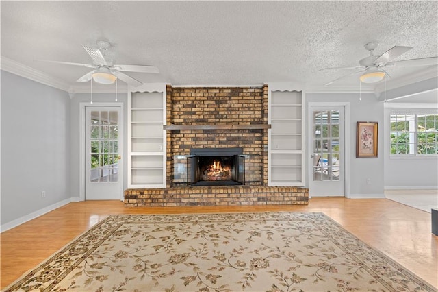 unfurnished living room with crown molding, built in shelves, a ceiling fan, and a textured ceiling