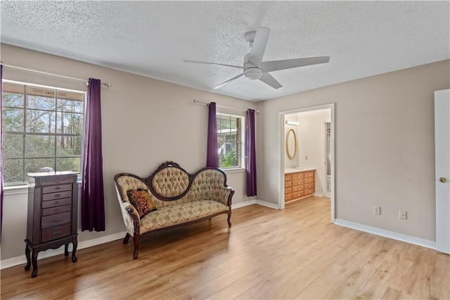 living area featuring baseboards, a textured ceiling, and light wood finished floors