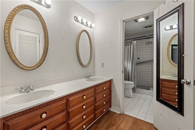 bathroom featuring double vanity, wood finished floors, a stall shower, and a sink