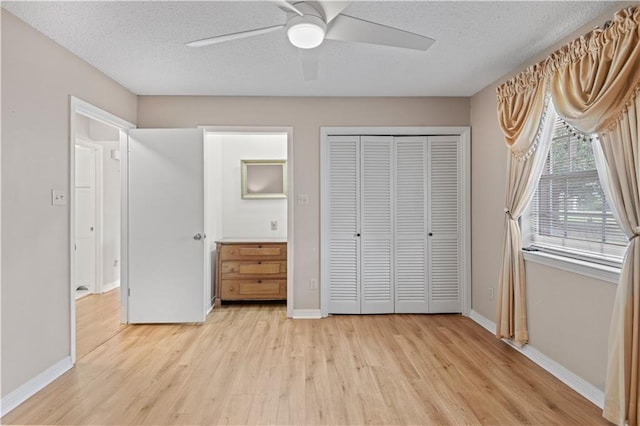 unfurnished bedroom with a closet, a ceiling fan, a textured ceiling, light wood-type flooring, and baseboards