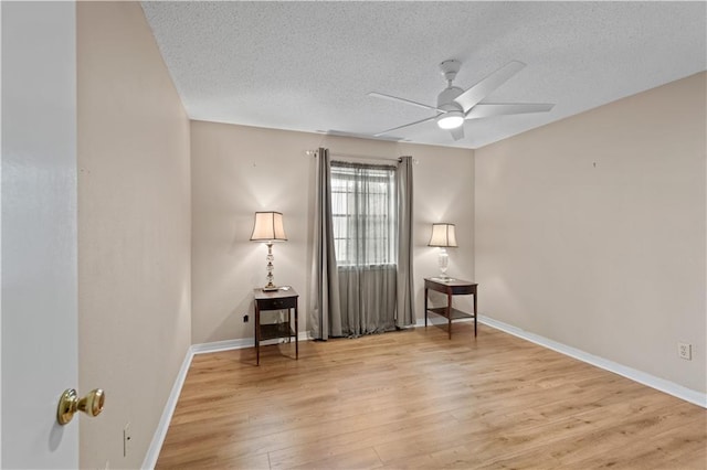 unfurnished room with a textured ceiling, ceiling fan, wood finished floors, and baseboards