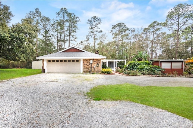 view of front facade with a chimney, gravel driveway, an attached garage, a front lawn, and brick siding