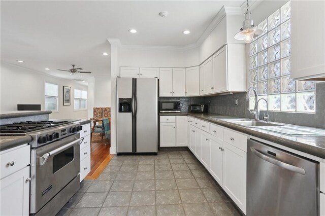 kitchen with appliances with stainless steel finishes, decorative light fixtures, white cabinetry, sink, and ornamental molding