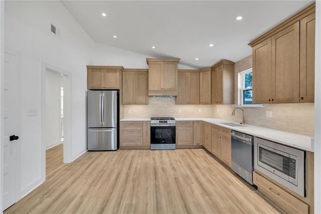 kitchen with lofted ceiling, sink, backsplash, light hardwood / wood-style floors, and stainless steel appliances