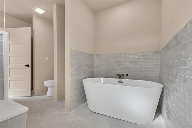 bathroom featuring toilet, a bathtub, and tile walls