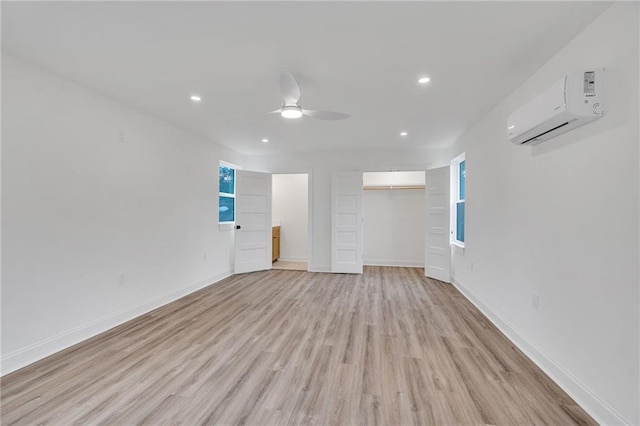 empty room featuring ceiling fan, light hardwood / wood-style floors, and a wall mounted AC