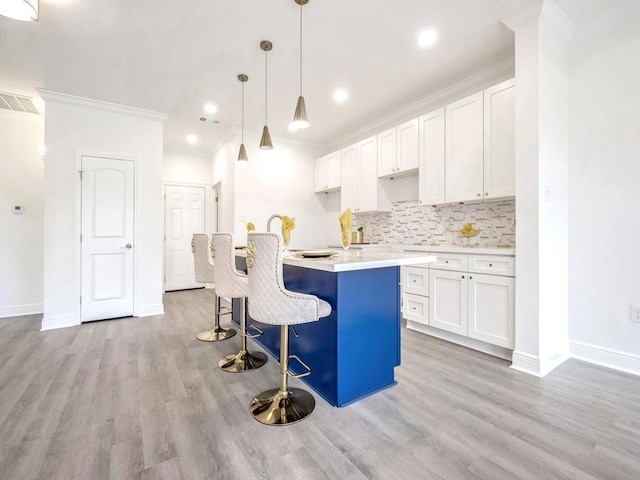 kitchen with pendant lighting, tasteful backsplash, white cabinets, and a center island with sink