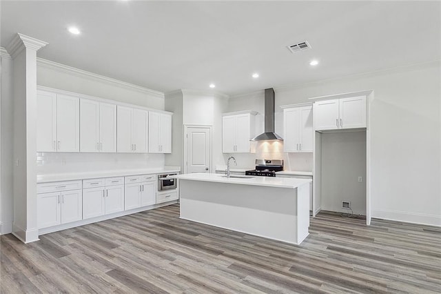 kitchen with wall chimney range hood, sink, white cabinetry, a center island with sink, and stainless steel electric stove