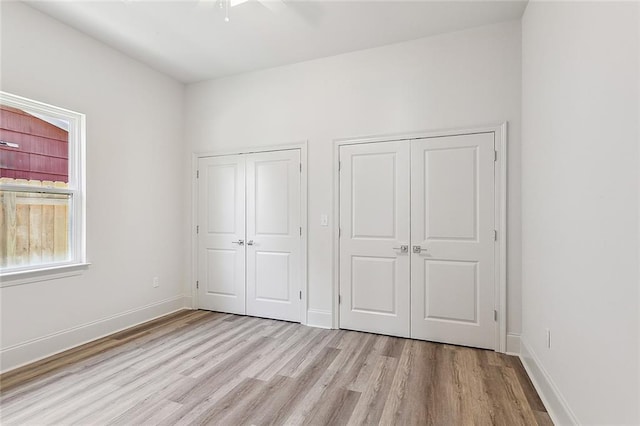 unfurnished bedroom with two closets, light hardwood / wood-style flooring, and ceiling fan