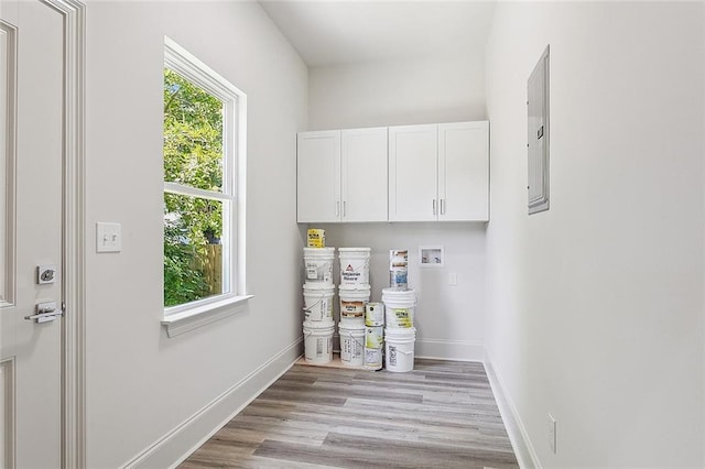 washroom featuring cabinets, hookup for a washing machine, electric panel, and light wood-type flooring