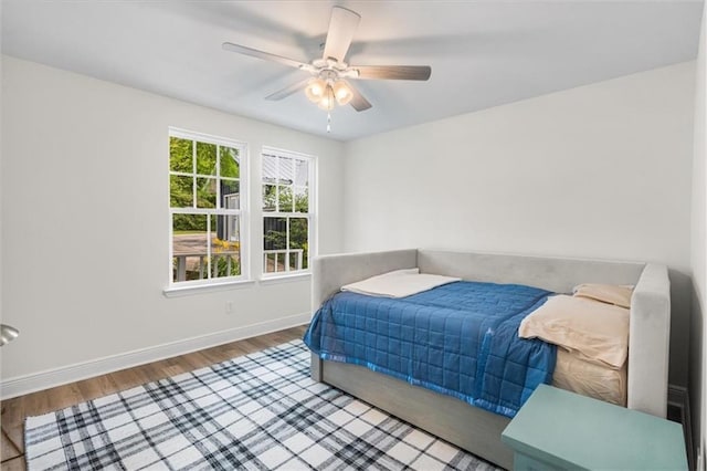 bedroom featuring wood finished floors, baseboards, and ceiling fan