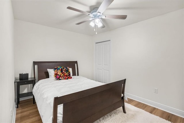 bedroom with a closet, ceiling fan, baseboards, and wood finished floors