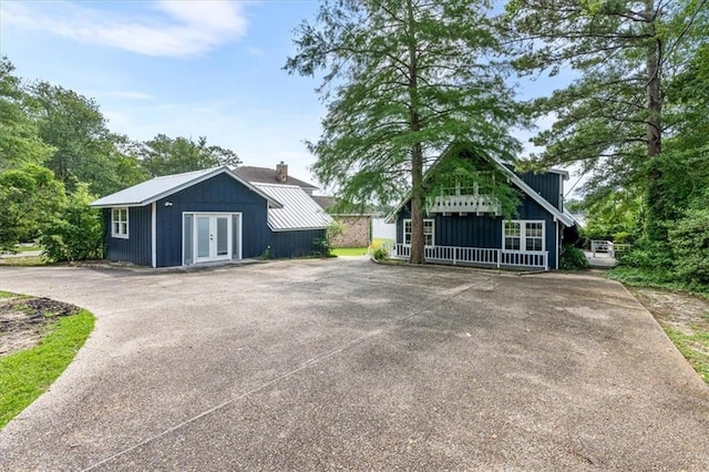 exterior space featuring french doors, board and batten siding, and driveway