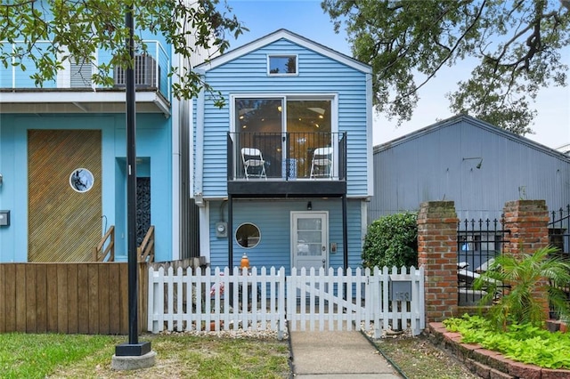 view of front of property featuring a balcony and a fenced front yard