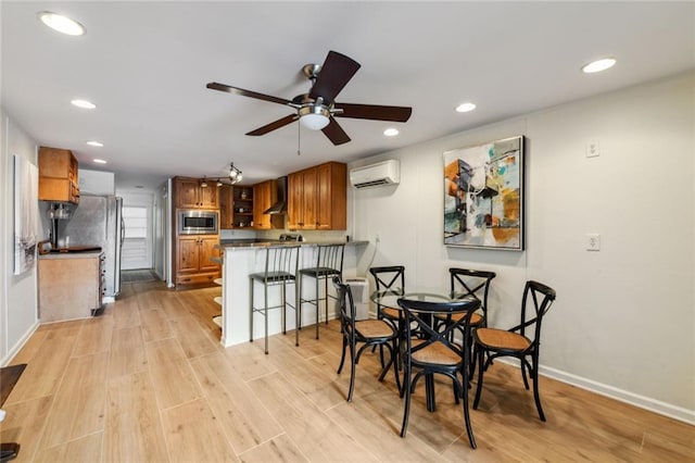 dining area featuring an AC wall unit, a ceiling fan, recessed lighting, light wood-style floors, and baseboards