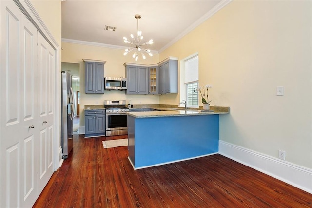 kitchen with appliances with stainless steel finishes, decorative light fixtures, dark hardwood / wood-style flooring, ornamental molding, and kitchen peninsula