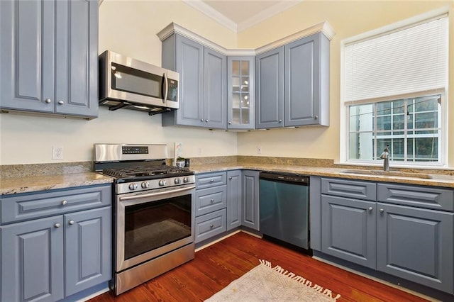 kitchen with sink, crown molding, dark wood-type flooring, gray cabinets, and stainless steel appliances