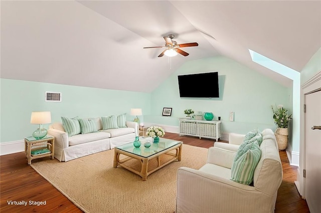 living room featuring hardwood / wood-style floors, vaulted ceiling with skylight, and ceiling fan