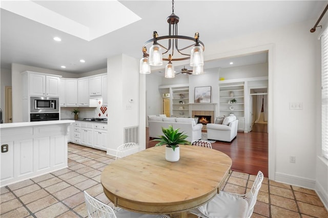 dining space with a fireplace, built in features, and a notable chandelier