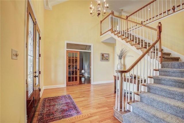 foyer featuring french doors, ornamental molding, wood-type flooring, and a notable chandelier