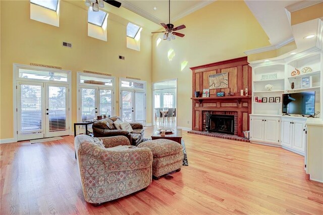 living room featuring light hardwood / wood-style floors, a fireplace, ceiling fan, and french doors