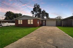 ranch-style home with a garage and a lawn